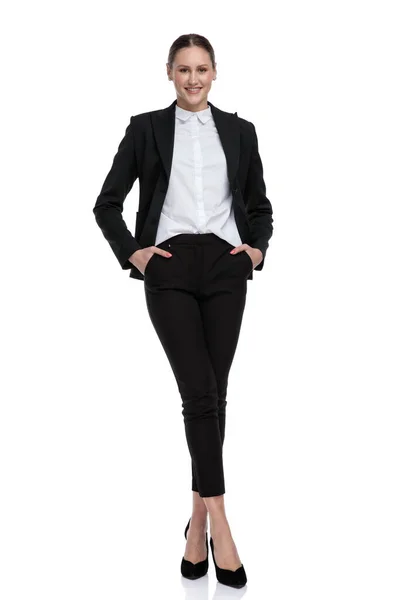 Businesswoman standing with crossed legs and hands in pockets — Stock Photo, Image