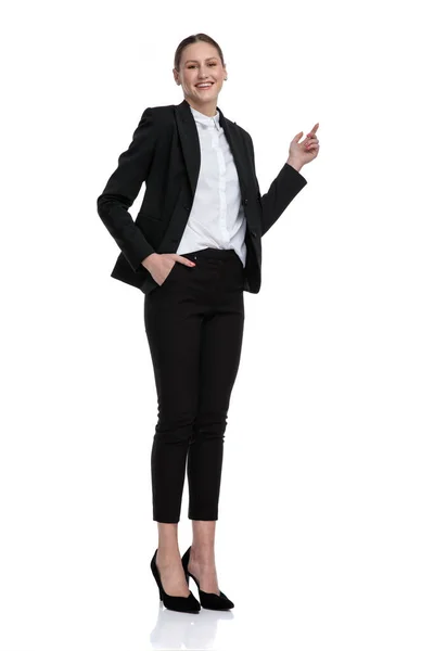 Businesswoman standing with hand in pocket and pointing up — Stock Photo, Image