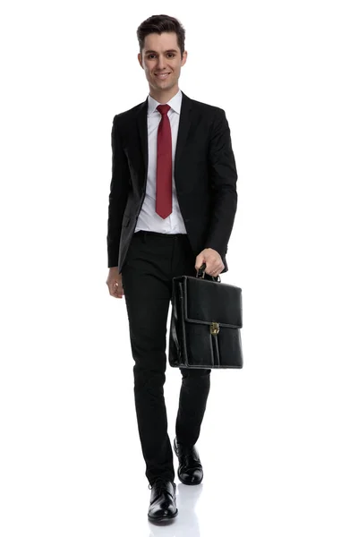 Hombre de negocios confiado sosteniendo un maletín y mirando hacia adelante —  Fotos de Stock