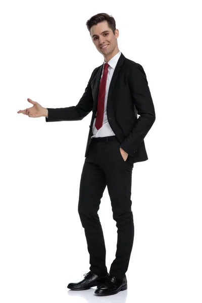 Positive young businessman presenting and standing — Stock Photo, Image