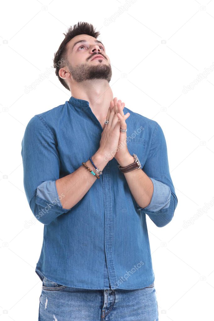 Hopeful casual man looking upwards and praying 