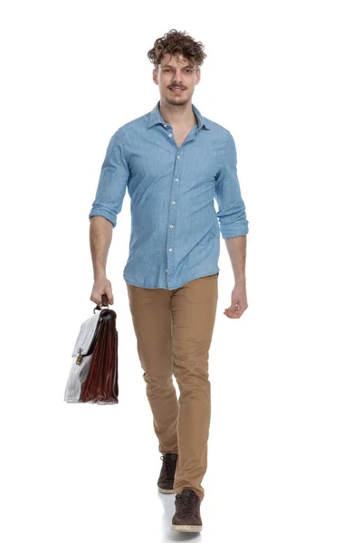 Zelfverzekerde Jonge Man Denim Shirt Met Koffer Glimlachen Lopen Geïsoleerd — Stockfoto