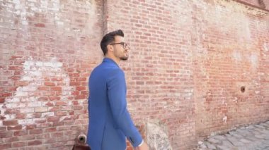 Yakışıklı, zeki, sıradan bir iş adamı. Duvara karşı yürüyor. Elinde evrak çantası, etrafa bakıyor.