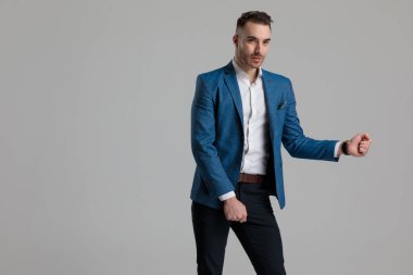 Gri arka planda dans etmek isteyen çekici bir genç adam.