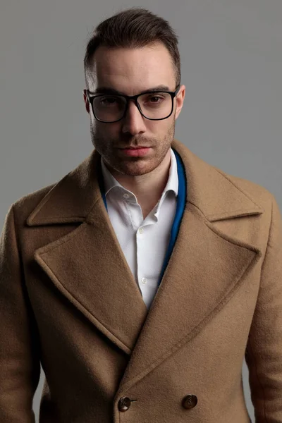 年轻聪明的休闲装模特 戴着眼镜和长大衣 站在灰色背景上 — 图库照片