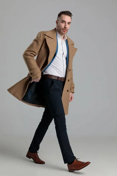 Atrakcyjny Smartcasual Mężczyzna Dostosowując Longcoat Chodzenie Boku Szarym Tle — Zdjęcie stockowe
