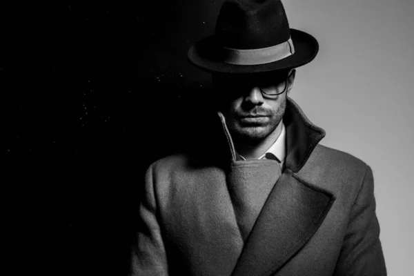 帽子と眼鏡をかけて黒い灰色の背景の影に立つ謎の青年 — ストック写真