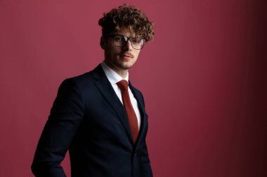 Seksi havalı iş adamı pozu veriyor, kameraya bakıyor ve pembe stüdyo arka planında denizci kıyafeti giyiyor.