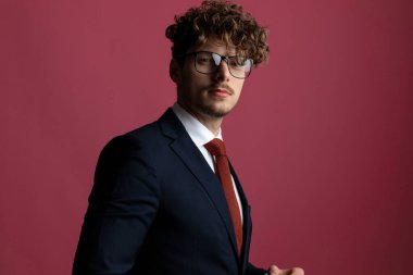 Genç yakışıklı iş adamı pembe stüdyo arka planında poz veriyor.