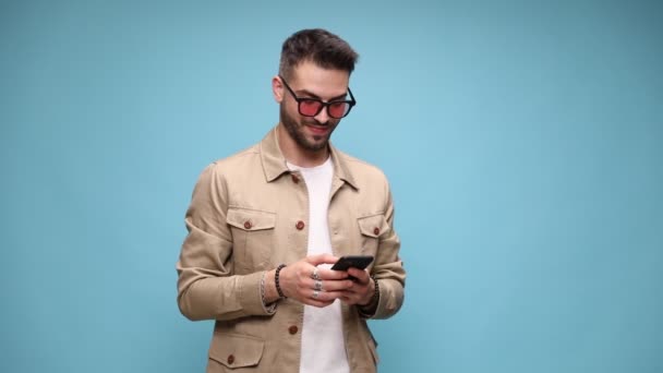 Enthousiaste Jonge Casual Man Draagt Jas Bril Kijkt Naar Telefoon — Stockvideo