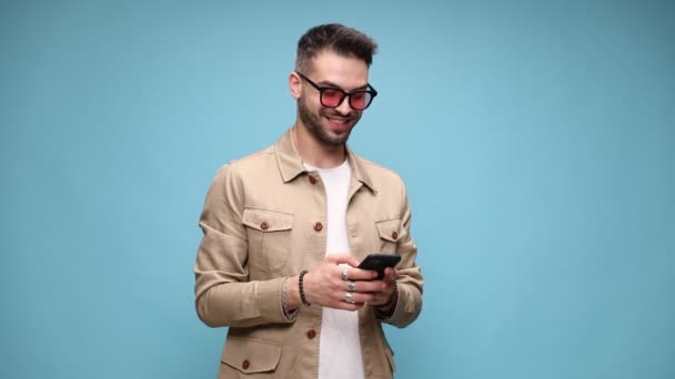 Podekscytowany Młody Mężczyzna Kurtce Okularach Patrząc Telefon Pisząc Wiadomości Wskazując — Wideo stockowe
