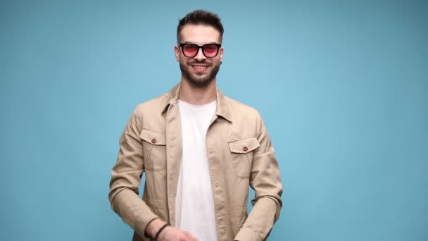 Poważny Młody Mężczyzna Kurtce Nosi Okulary Zaczyna Się Uśmiechać Skrzyżowanie — Wideo stockowe