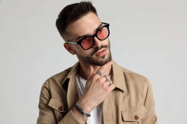 Thoughtful Unshaved Young Man Jacket Wearing Sunglasses Touching Chin Thinking — Stock Photo, Image