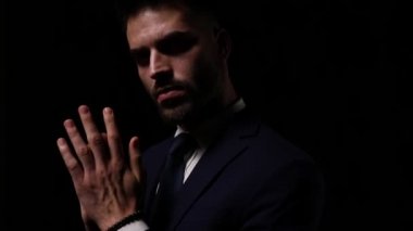 Gizemli genç iş adamının avuçlarını ovuşturması, merak etmesi, denetlemesi, dönmesi ve karanlıkta kaybolması.