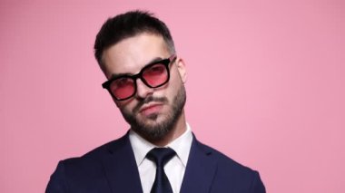 Güneş gözlüğü takan, tavır takan, dudaklarını pembe arka planda baştan çıkaran seksi bir iş adamının fotoğrafını çek.