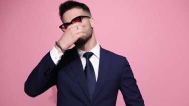 Zeki sıradan iş adamı saçını düzeltir, güneş gözlüğü takar, ceketini düzeltir, kollarını kavuşturur ve sert bir tavırla poz verir sonra da pembe arka planda kahkahalara boğulur.