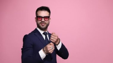 Çekici iş adamı görünmez bir halat çekiyor, onun yakalanmasına bakıyor sonra parmaklarını öpüyor ve öpücüklerini pembe arka planda her yere yayıyor.