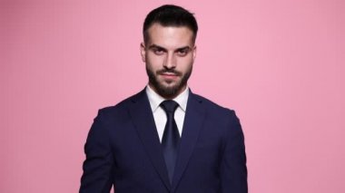 Pembe arka planda duran işadamı, gülümsüyor ve ileriye bakıyor.