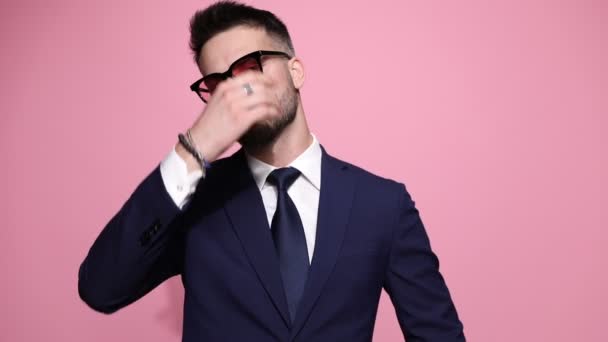 사업가가 선글라스를 양팔을 태도로 포즈를 취하고는 분홍색 배경에 웃음을 터뜨린다 — 비디오