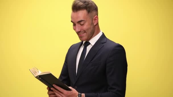 Glückliches Junges Mode Model Anzug Liest Buch Lächelt Und Zeigt — Stockvideo