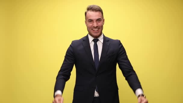空中で拳を握り笑い見上げ黄色い背景で勝利を祝うスーツ姿のエレガントなビジネスマン — ストック動画