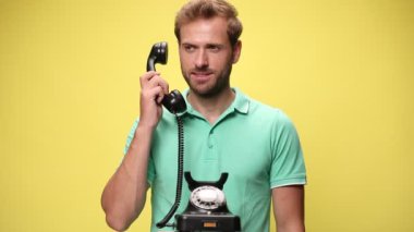 Sıradan bir genç adam eski telefonu kaldırıyor, kötü haberler duyuyor, yüzünü ekşitiyor ve sarı arka planda onaylamıyor.