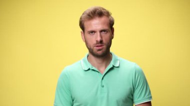 Korkmuş genç, sıradan bir adam ağzını korkunç bir şekilde açıyor, ellerini havaya kaldırıyor ve sarı arka planda teslim oluyor.