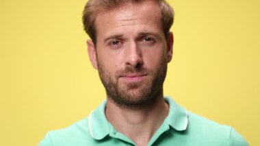 Gülümseyen, gülen, yükselen kaşları sarı arka planda duran sıradan genç adama yakın durun.