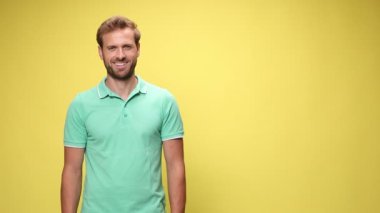 Sıradan bir adam gülümsüyor, parmaklarını sağa sola gösteriyor ve sarı arka planda baş parmak hareketi yapıyor.