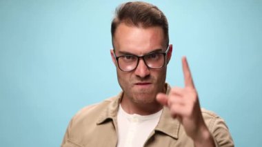 Çekici, sıradan bir adam, dikkat çekmek istiyor, sonra diğer parmağıyla işaret ediyor, ve mavi arka planda açık bir işaret veriyor.