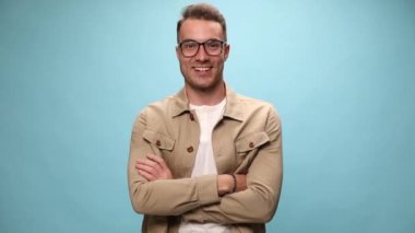 Kolları çapraz genç adam gülümseyerek ve zaferleri kutlarken mavi arka planda yumruklarını kaldırdı.