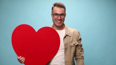 Çekici, sıradan bir adam havada yumruğunu sallıyor ve başarıları kutluyor, mavi arka planda büyük kırmızı bir kalp tutuyor.