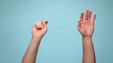 Tek elle kameraya doğru iki kol, sonra ikisi de işaret ediyor. Bana işaret ediyor ve mavi arka planda yumruklar sallıyor.