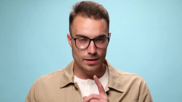 Ceket Gözlük Takan Genç Bir Adam Mavi Arka Planda Sessizlik — Stok video
