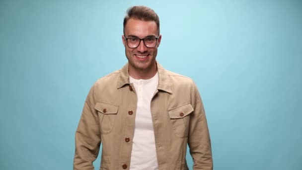 Młody Mężczyzna Spogląda Dół Patrzy Kamerę Uśmiecha Się Krzyżuje Ramiona — Wideo stockowe