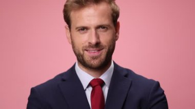 Donanma mavisi takım elbiseli, pembe arka planda gülümseyen ve parmakla işaret eden zarif genç işadamına yakın durun.