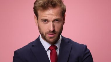 Lacivert takım elbiseli, gülümseyen, gülen, yumruklarını tutan ve pembe arka planda zafere tezahürat eden genç, zarif iş adamını yakından takip edin.