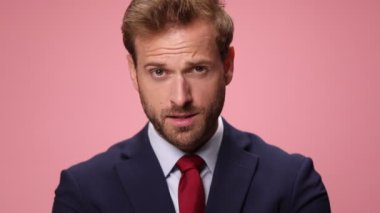 Donanma mavisi takım elbiseli zarif genç işadamlarına yakın çekim. Şaşırtıcı bir şekilde ağzını açıyor, yumruklarını kaldırıyor ve pembe arka planda zafere tezahürat yapıyor.