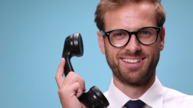 Eski telefona cevap veren, gülen, konuşan, telefonu kapatan ve mavi arka planda baş parmağını sallayan işadamlarına.