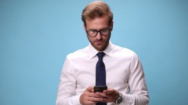 Çekici iş adamı telefonuna bir mesaj yazıyor ve mavi arka planda başarıları kutluyor.