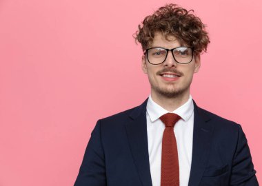 Gözlük takan ve pembe arka planda gülümseyen zarif bir iş adamı.