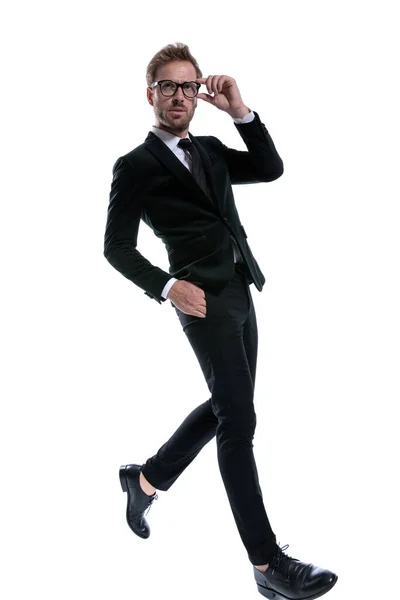 穿着黑色西服 手插在口袋里 自信地走在白色背景上 浑身是劲十足的时尚男子的侧面形象 — 图库照片