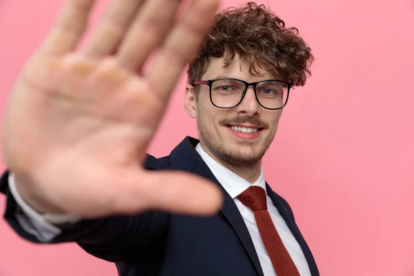 happy young businessman in navy blue suit wearing glasses, framing and smiling on pink background