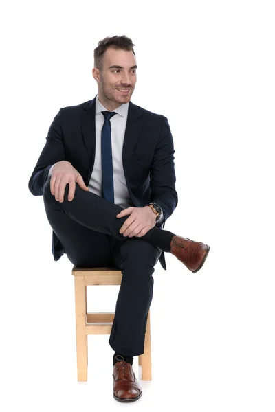 一个积极向上的商人坐在白色的工作室背景的椅子上 面带微笑地望着别处 — 图库照片