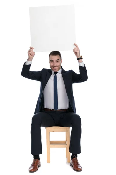Щасливий Бізнесмен Тримає Порожній Рекламний Щит Посміхається Сидячи Стільці Білому — стокове фото