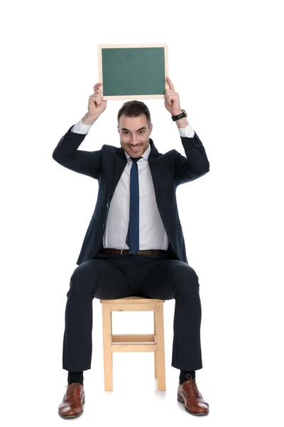 Šťastný Podnikatel Usmívá Drží Tabuli Nad Hlavou Zatímco Sedí Židli — Stock fotografie