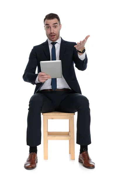 紧张的商人拿着平板电脑 坐在白色工作室背景的椅子上感到害怕 — 图库照片