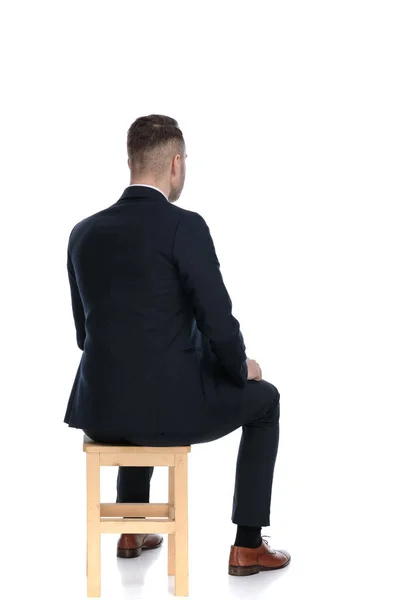 白いスタジオの背景に椅子に座っているハンサムなビジネスマンの背面図 — ストック写真