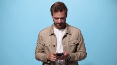 Telefonuyla mesajlaşırken gülümseyen sıradan bir adam, sonra şok ve heyecanla mavi arka plandaki başarıları kutluyor.