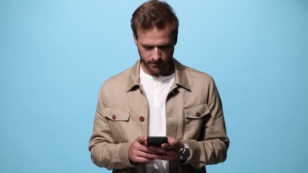 Hombre Casual Mensajes Texto Teléfono Contra Fondo Azul Riendo Luego — Vídeo de stock